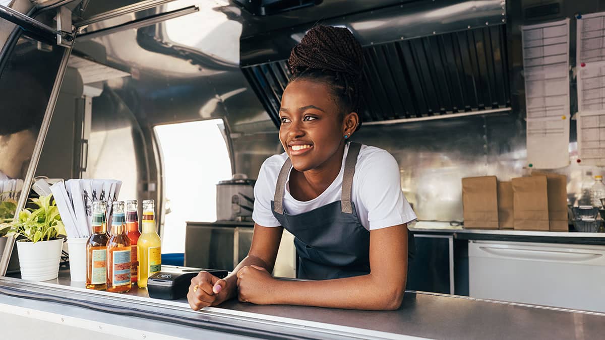 Female hospitality worker smiling from a street food vehicle