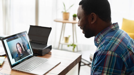 A man on at a desk with an open laptop on a  video call with a woman